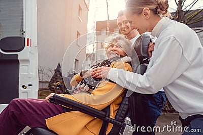 Senior woman in wheelchair being picked up by transport service Stock Photo