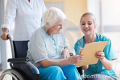 Senior woman in wheelchair with nurse in hospital Stock Photo