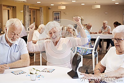 Senior Woman Winning Game Of Bingo In Retirement Home Stock Photo