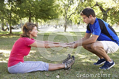 Senior Woman Working With Personal Trainer In Park Stock Photo