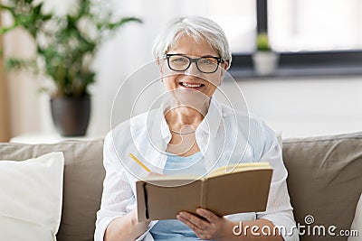 Senior woman writing to notebook or diary at home Stock Photo