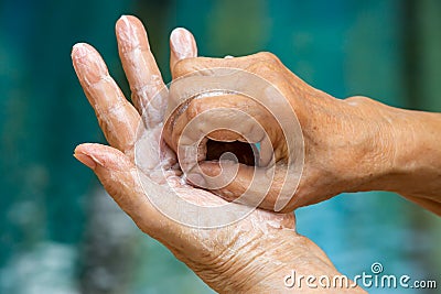 Senior woman& x27;s hands washing her hands using soap foam in step 6 on bokeh blue swimming pool, Prevention from covid19 Stock Photo