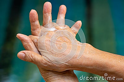 Senior woman& x27;s hands washing her hands using soap foam in step 2 on bokeh blue swimming pool, Prevention from covid19 Stock Photo