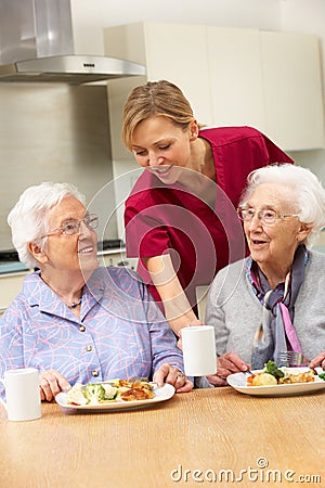 Senior women with carer enjoying meal at home Stock Photo