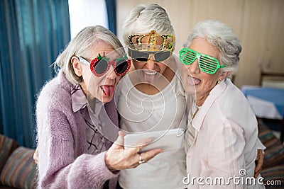 Senior women wearing novelty glasses making face while taking selfie Stock Photo