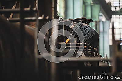 Senior worker in a dirty and old but still functioning metal works, old fashioned, factory Editorial Stock Photo
