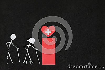 Seniors or old people access to healthcare concept. Elderly couple stick figure beside red health icon in dark black background Stock Photo
