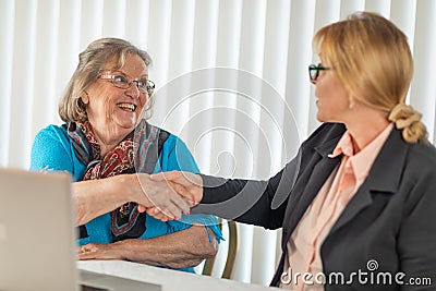 Senior Woman Shaking Hands with Businesswoman Near Laptop Computer Stock Photo