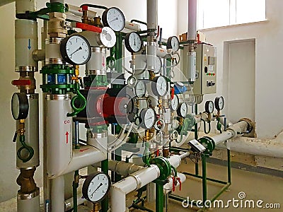 Sensors and devices indicating the parameters of hot water in the heating system of a large house. Interlacing of pipes. Technical Stock Photo