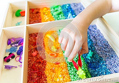 Sensory box with rainbow rice inside. Montessori material baby Stock Photo