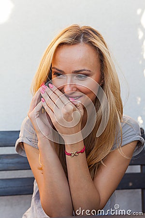 Sensual blonde woman sitting on wooden bench. She is using mobile phone Stock Photo