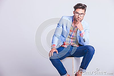 Sensual casual man wearing glasses and jeans seated Stock Photo