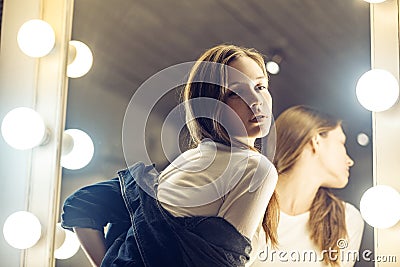 Sensual cute girl in blue jacket ready for romantic date. Adorable young woman posing near the makeup mirror in her room with sen Stock Photo