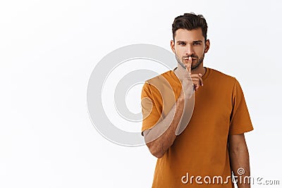 Sensual and dreamy handsome bearded man in brown t-shirt, shushing and squinting passionatly, keep secret, asking be Stock Photo