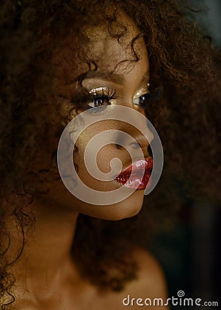 Sensual portrait of magic surreal golden african american female model with bright glitter makeup, glossy golden Stock Photo