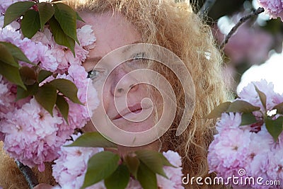 Sensual portrait of a sexy, soulful, pensive, mature redhead woman, best age, behind pink flower tree blossoms, spring awakening, Stock Photo