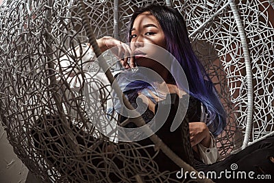 sensual seductive woman with colored hair sitting in rattan chair Stock Photo