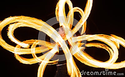 Sensual woman artist perform fiery twirly trails by spinning flaming pois during fire performance in night darkness Stock Photo