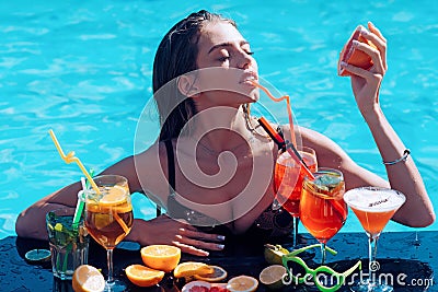 Sensual woman with grapefruit. Young woman with coctails. Wet girl drink cocktail in swimming pool. Stock Photo