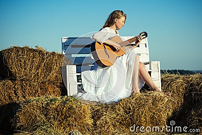 Sensual woman play guitar on wooden bench. Woman guitarist perform music concert. Albino girl hold acoustic guitar Stock Photo