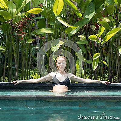 Sensual young woman relaxing in outdoor spa infinity swimming pool surrounded with lush tropical greenery of Ubud, Bali. Stock Photo