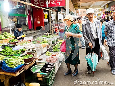 Seoul, South Korea - June 26, 2017: Elderly woman buys vegetables and greens at Gwangjang Market in Seoul Editorial Stock Photo