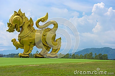 2018 September 29. CHIANG RAI THAILAND. A big golden lion statue standing at green grass yard and surrounded by natural mountain a Editorial Stock Photo