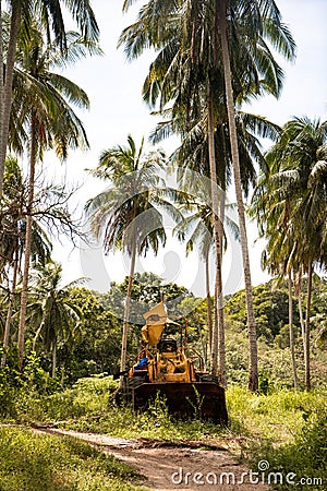 September 25, 2020: Pulau Redang Terengganu, Malaysia: Abandoned yellow backhoe on the land with coconut tree as a background Editorial Stock Photo