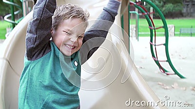 Sequenza del movimento lento del ragazzo che gioca sullo scorrevole in campo da giuoco stock footage Sequenza del movimento lento del ragazzo che gioca sullo scorrevole in campo da giuoco stock footage