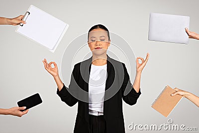 Serene Asian businesswoman in a meditative pose surrounded by office items Stock Photo