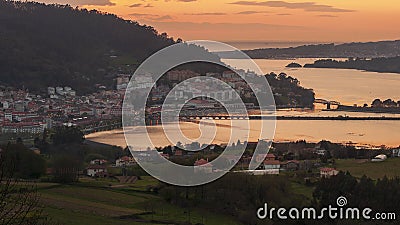 Serene dusk view of the medieval fishing town of Pontedeume with its iron and stone bridge orange sky La CoruÃ±a Galicia Stock Photo