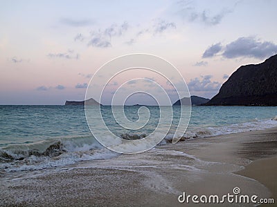 Serene Dusk at Waimanalo Beach with Lapping Waves and Rabbit Island in the Distance Stock Photo