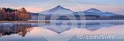 Serene high tatra lake in early autumn sunrise over pine forest, ideal nature hiking adventure Stock Photo