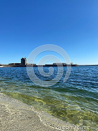 Serene shoreline of a tranquil sea with buildings in the background Stock Photo