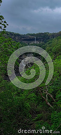 Serene Waterfall in Lush Green Forest With Overcast Dramatic Sky Stock Photo