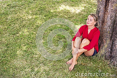 Serene young woman enjoying summer freshness under a tree Stock Photo