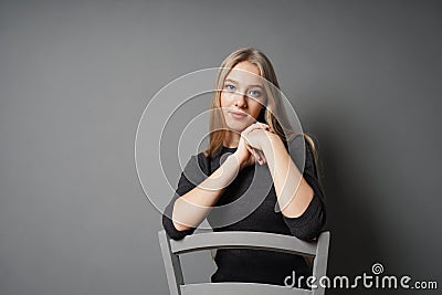 Serene young woman sitting astride on chair Stock Photo