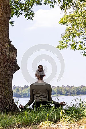 Serenity in Nature: Young Woman Meditating by the Forest Lake Stock Photo