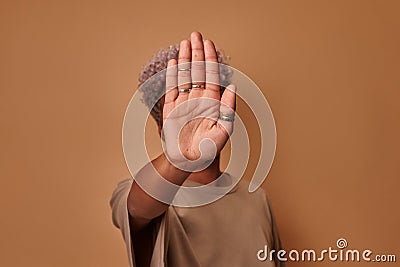 African woman showing stop sign with palms on beige background Stock Photo