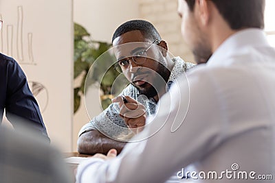 Serious african boss talking to diverse employees at group meeting Stock Photo