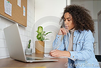 Serious african teen girl college student elearning at home making notes. Stock Photo