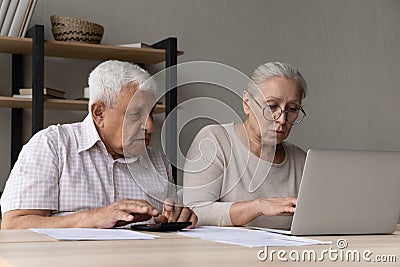 Serious aged spouses sit at desk manage household finances Stock Photo