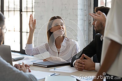 Serious ambitious businesswoman raise hand ask question to diverse presenter. Stock Photo