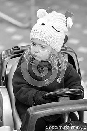 Serious and attentive baby girl driver observing traffic regulations. Black and white candid portrait of a child in the park Stock Photo