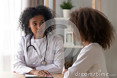 Serious black female doctor consult teenage girl Stock Photo