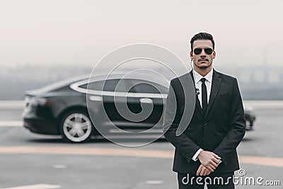 serious bodyguard standing with sunglasses and security earpiece Stock Photo