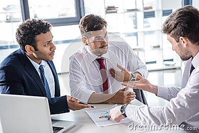 Serious business people sitting at table and discussing diagrams in office Stock Photo