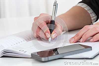 Serious business woman writting on her agenda in the office Stock Photo