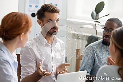 Serious businessman talking with group of business partners at meeting Stock Photo