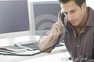 Serious Businessman Using Landline Phone At Desk Stock Photo